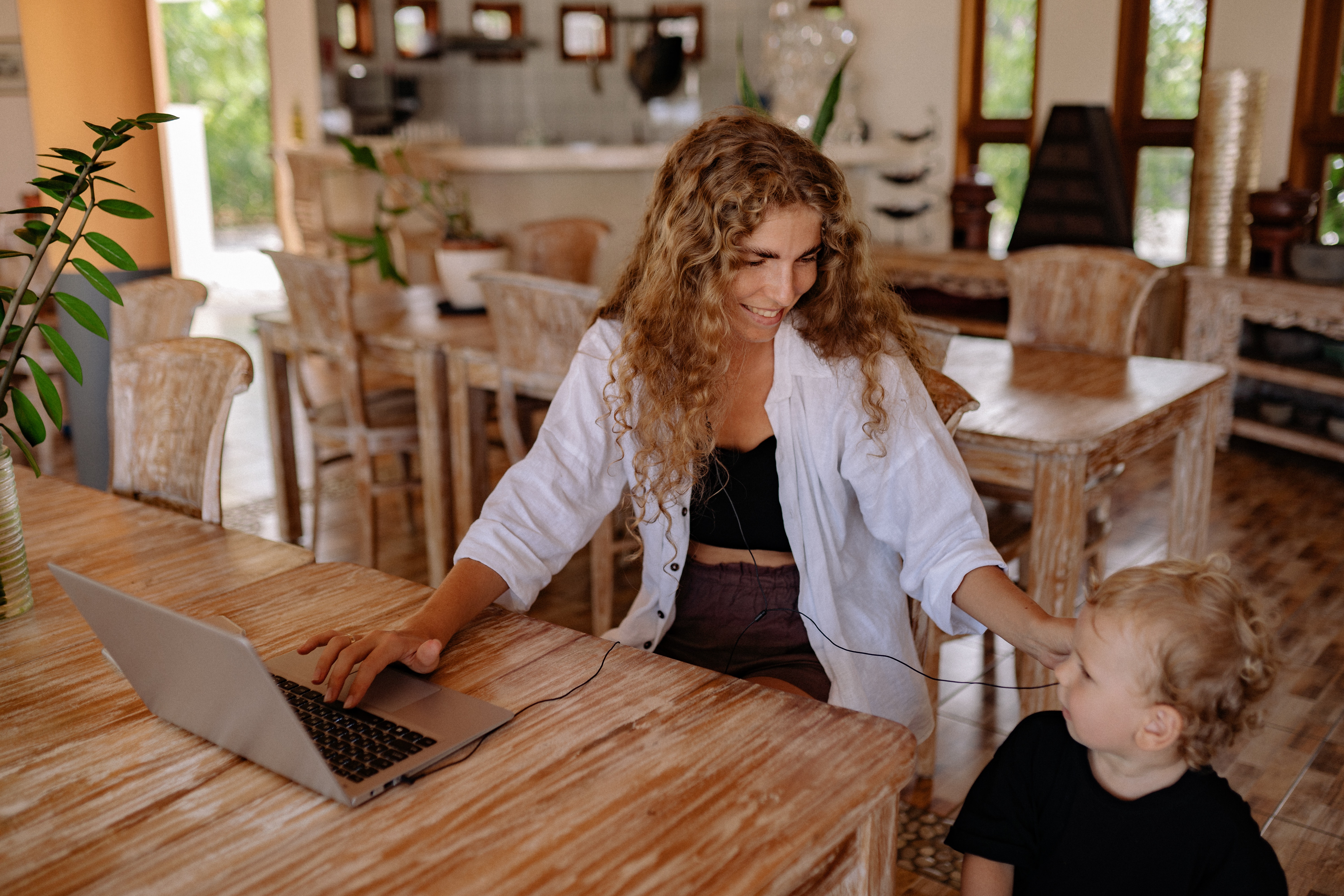 Working mom with curly hair and son using financial wellbeing benefits on her laptop